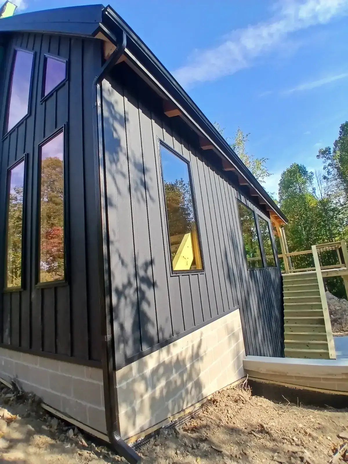 Black board and batten metal siding and gutter on a wooded Ohio property in autumn